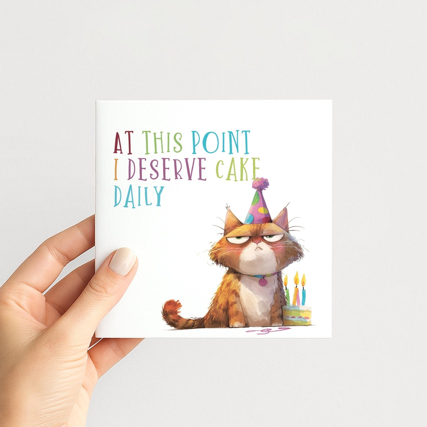 Funny Cat Birthday Card by Whimsi Lilley featuring a humorous design and message about deserving cake daily.
