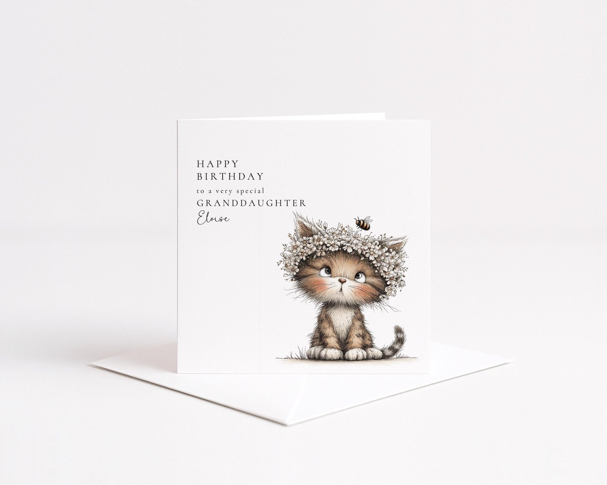 A birthday card featuring a cute cat wearing a flower crown and sitting on the ground.