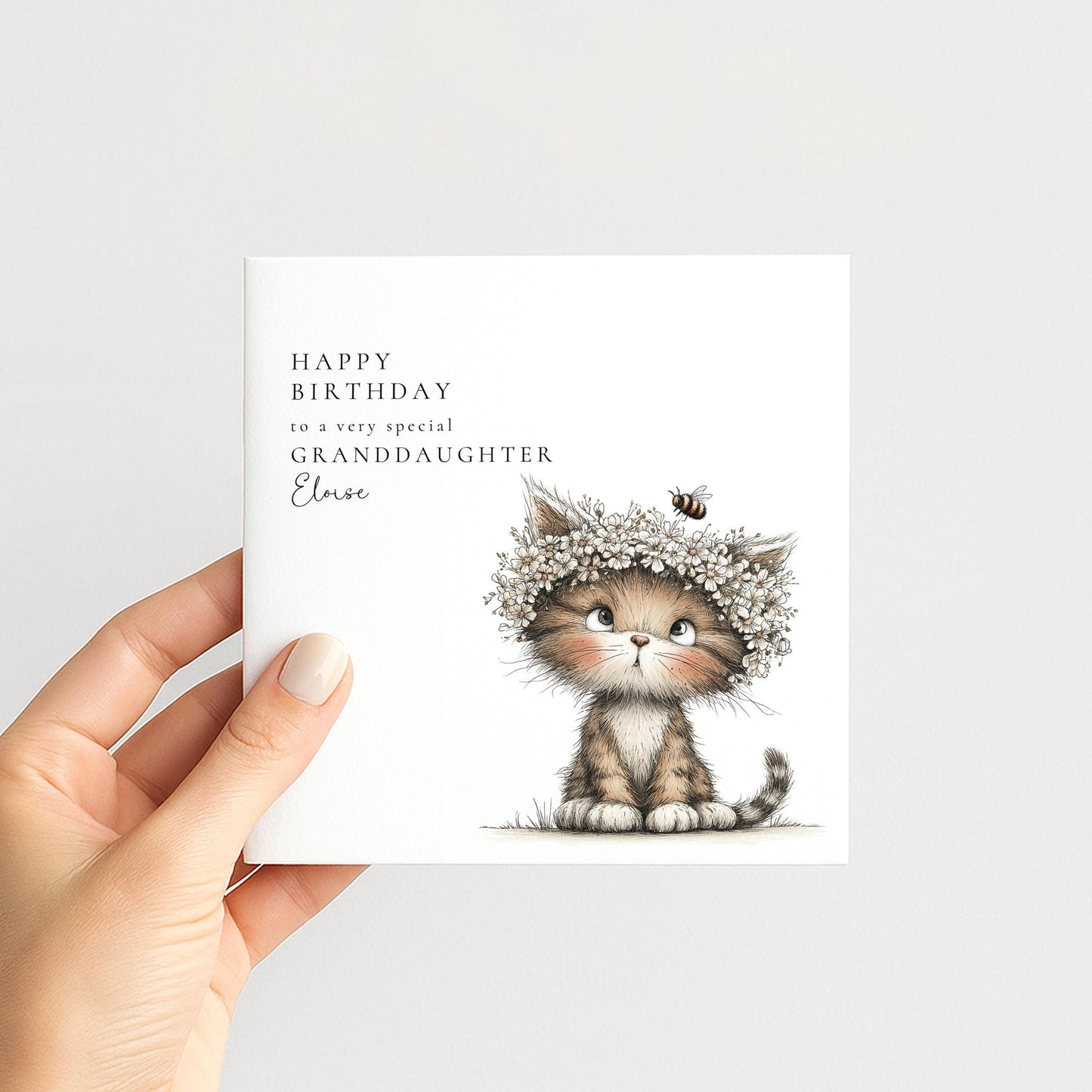 A hand holding a birthday card with a cute cat wearing a flower crown.
