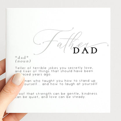 a person holding a card with the word "DAD" written on it. The card contains a definition of "DAD" and some personal reflections about the role of a father.
